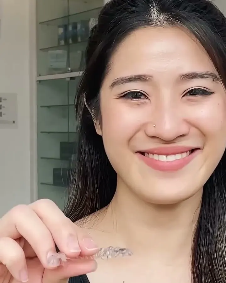 Smiling patient holding a clear aligner